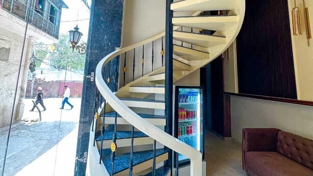 Una escalera espiral moderna con barandilla de vidrio, suelo de mármol y un sofá en el vestíbulo.
