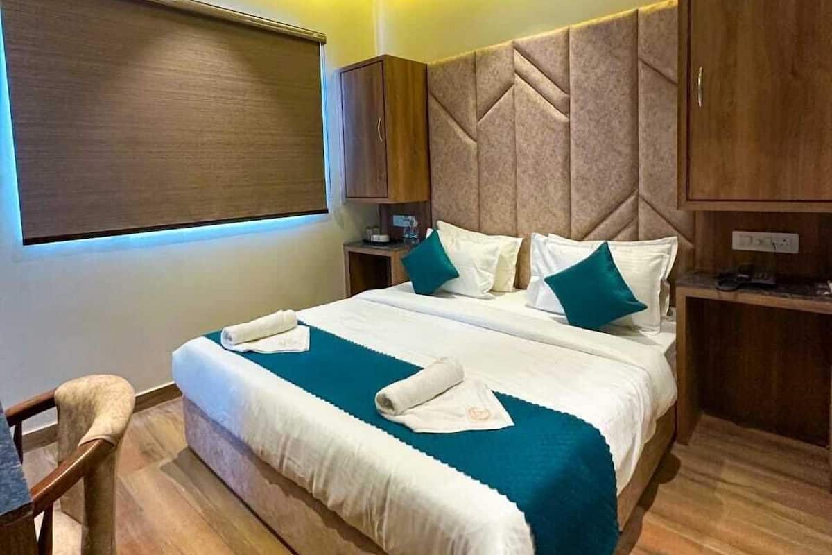 A hotel room with a large bed, wooden headboard, a desk, and a chair.
