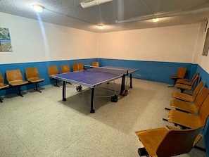 A ping pong table in a room with blue and white walls, surrounded by wooden chairs.