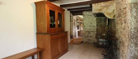 Un interior rústico con paredes de piedra vista, un aparador de madera, un banco y una máquina de coser antigua.