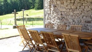 Un muro de piedra con una mesa y sillas de madera en un entorno al aire libre.