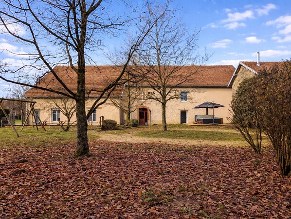 Une maison à deux étages, avec un toit recouvert de tuiles, une porte d  ’entrée et un petit porche.