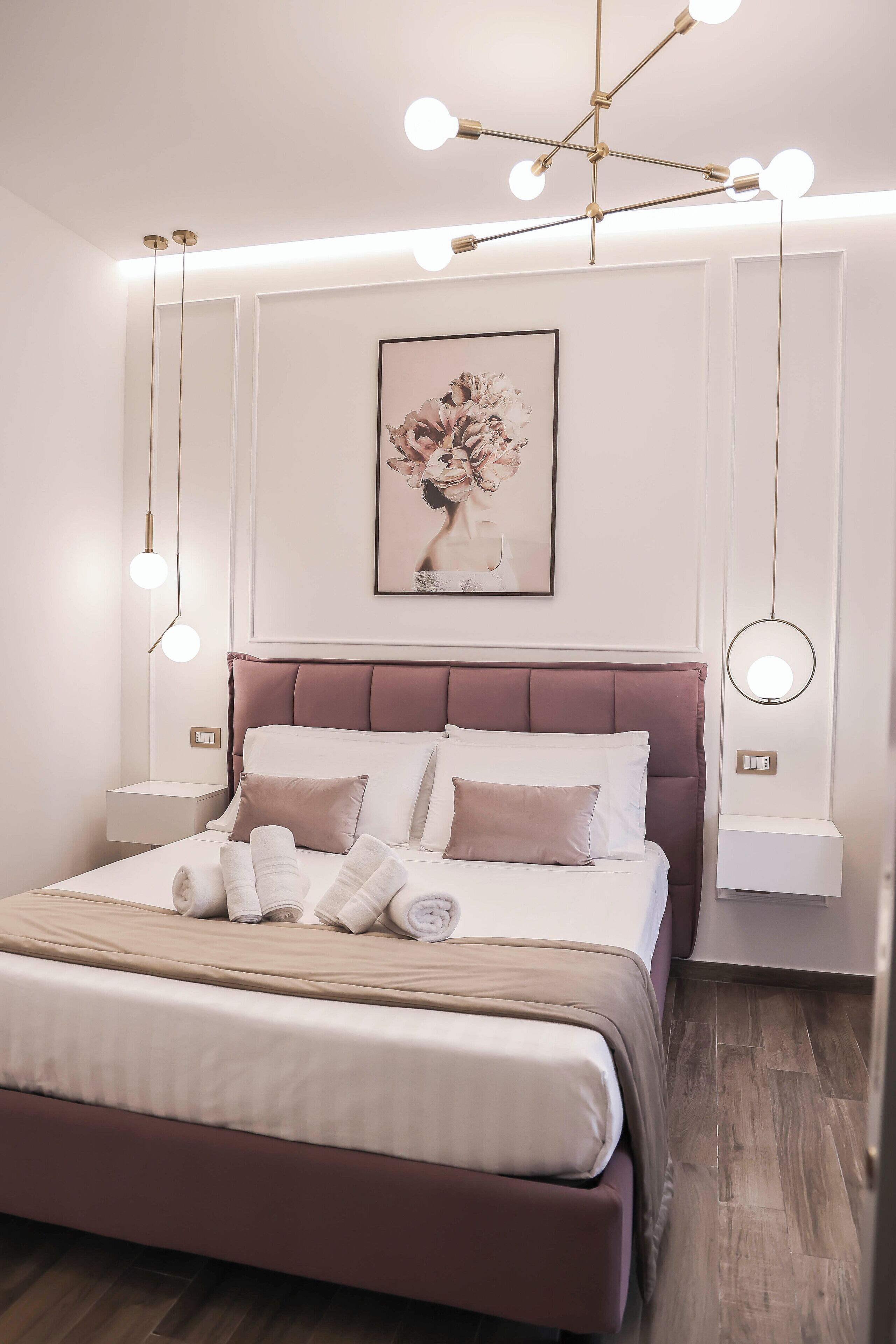 A modern bedroom with a large bed, a headboard, bedside tables, and a wall-mounted artwork.