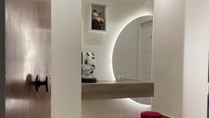 Et moderne badeværelse med en trækommode, et spejl og en rød skammel.
