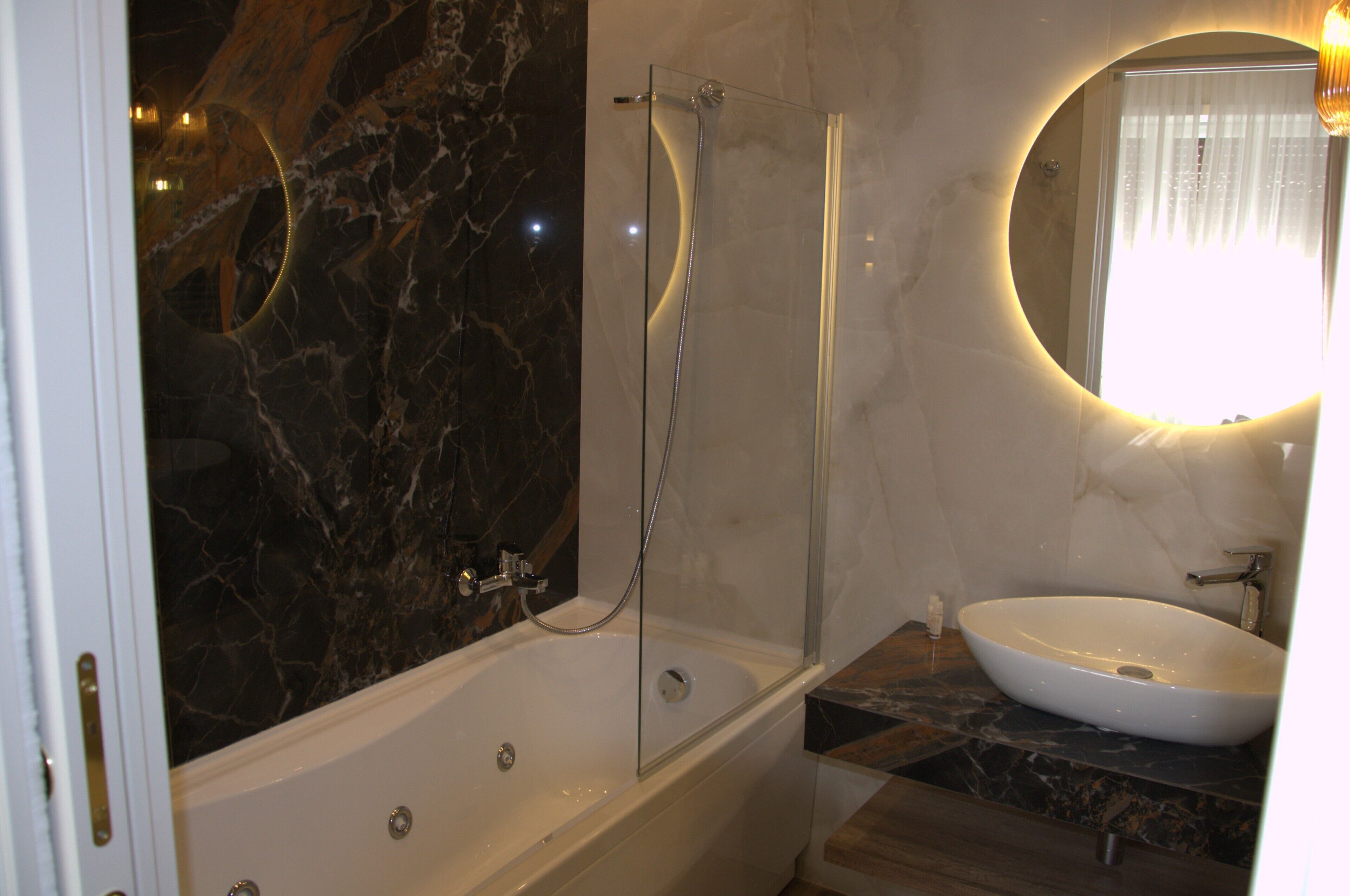 A bathroom with a bathtub, a glass-enclosed shower, a sink, and a mirror.