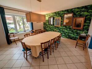 Un espace repas comprenant une table ronde, des chaises, un luminaire suspendu et un mur orné de miroirs encadrés.
