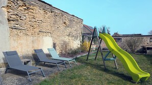 A stone wall, a yellow slide, and three lounge chairs.