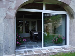 Una entrada de piedra con arco y puerta de vidrio que da a un patio al aire libre.