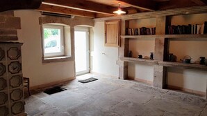 Een rustieke kamer met stenen vloer, houten plafond en een boekenplank vol boeken.