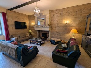 Una sala de estar con chimenea, sofás, una mesa de centro y un televisor.