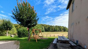 Un jardin avec une balançoire, une table de pique-nique et un banc en pierre.