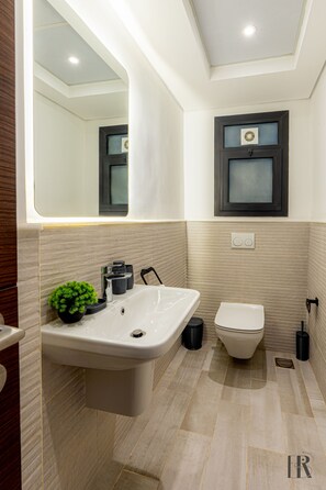 A modern bathroom with a white sink, a toilet, and a mirror. - Easy Rental/ Serviced Apartment In CFC New Cairo (New Cairo City)