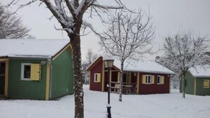 Un paisaje nevado con una cabaña roja y un edificio verde.