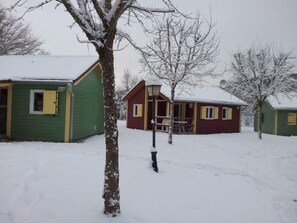 Un paysage enneigé avec une cabane rouge et un bâtiment vert.