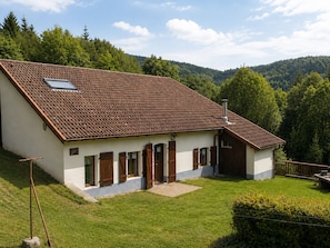 A two-story house with a sloped roof, a small attached garage, and a well-maintained lawn.