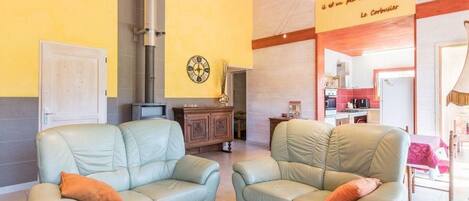 A cozy living room with two light green sofas, a wooden cabinet, and a yellow wall with a clock.