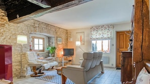 A cozy living room with a stone wall, a television, a sofa, and a red refrigerator. - Quiet cottage near Villersexel, nature and activities (Esprels)