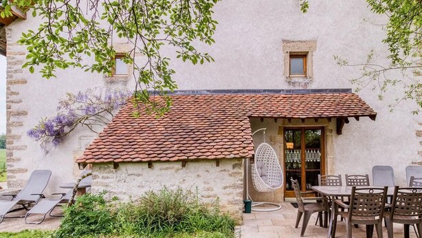 A stone building with a tiled roof, a hanging chair, and a table with chairs outside. - Quiet cottage near Villersexel, nature and activities (Esprels)