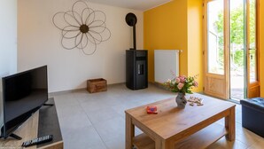 Un salon avec un téléviseur, des meubles en bois, un vase à fleurs et une grande œuvre d’art murale représentant des fleurs.