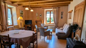 Un intérieur en bois comprenant une table à manger, des chaises, un canapé, un téléviseur et une cheminée.