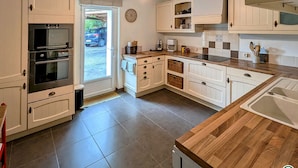 Une cuisine moderne avec des meubles blancs, un plan de travail en bois et un four encastré.