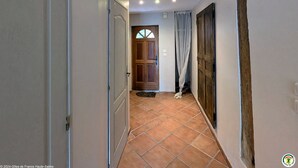 Un couloir avec un sol carrelé, une porte en bois et une porte blanche.