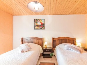 A room with two wooden beds, a nightstand with a lamp, a painting on the wall, and a wooden ceiling. - Charming Cottage in the Vosges Saônoises (Saint-Bresson)