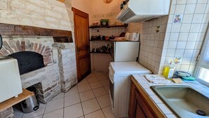 Una cocina con pared de piedra, puerta de madera, refrigerador blanco y salpicadero de azulejos.