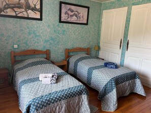 A bedroom with two wooden beds, a wardrobe, and two framed pictures on the wall.