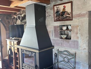 A kitchen with a built-in stove, a television on a cabinet, and a decorative rooster painting on the wall. - Family cottage for 8, historic charm & modern comfort (Fresse)