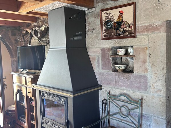 A kitchen with a built-in stove, a television on a cabinet, and a decorative rooster painting on the wall.