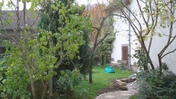 A pathway leading to a white building with a tiled roof.
