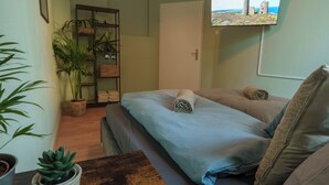 A bedroom with a bed, a TV mounted on the wall, a potted plant, and a wooden table. - Castora Homes - City Apartment Kassel near train station (Kassel)