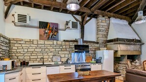 A rustic kitchen with stone walls, a wooden table, and a stone fireplace. - Welcoming lodge perfect for hikers with pets allowed (Fretigney-et-Velloreille)