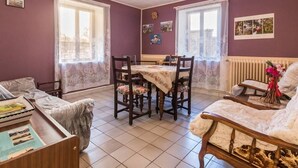 Een gezellige woonkamer met een eethoek, voorzien van een open haard, een bank, een salontafel en een eettafel met stoelen.