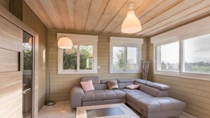 Un salon moderne avec un canapé d’angle, une table basse et de grandes fenêtres qui laissent entrer la lumière naturelle.