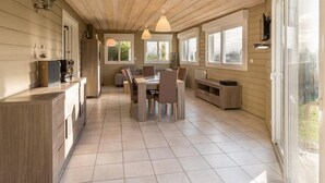 Une cuisine moderne avec des meubles en bois, un coin repas comprenant une table et des chaises, et de grandes fenêtres qui laissent entrer la lumière naturelle.
