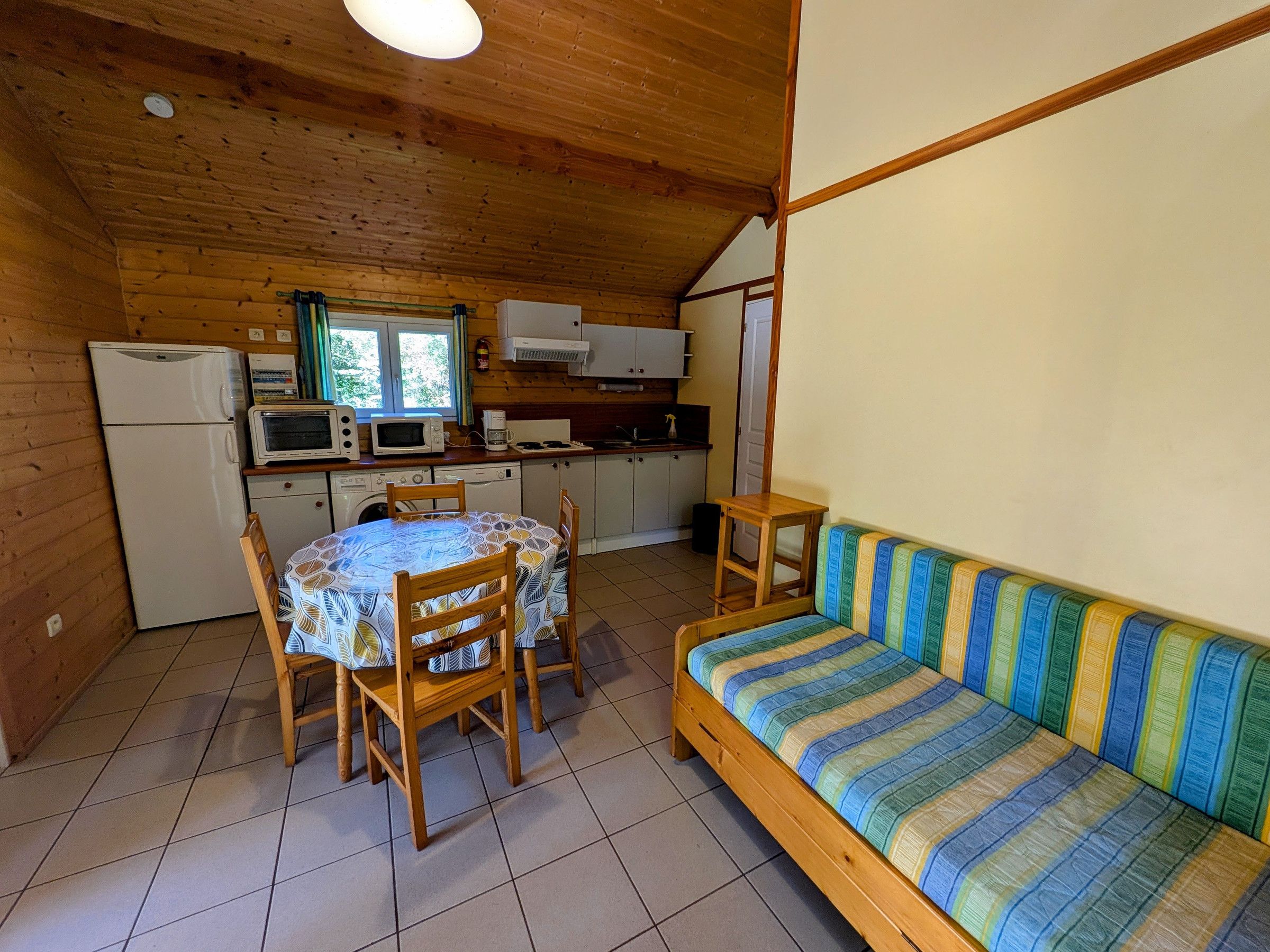 A compact kitchen with a dining table and chairs, a sofa, and a microwave.