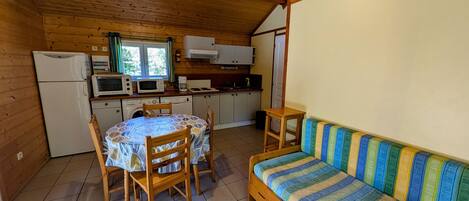 A compact kitchen with a dining table and chairs, a sofa, and a microwave.