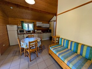 Cocina compacta con mesa y sillas, un sofá y un microondas.