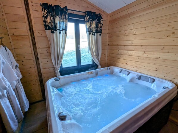 A wooden cabin with a hot tub, curtains, and towels.