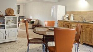 Un espacio habitable compacto con comedor, cocina y zona de estar con sofá y sillas.