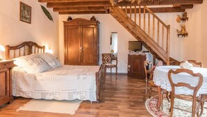 Un dormitorio acogedor con una cama de madera, un armario, una mesa de comedor con sillas y una escalera.