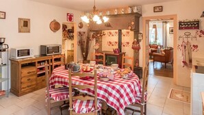 Una cocina acogedora con una mesa de comedor preparada para una comida, un microondas, un tostador y varios utensilios de cocina.