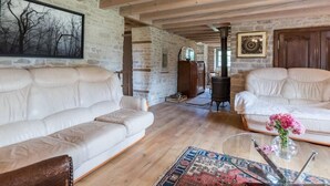 A spacious living room with a stone wall, wooden beams, and a large window.