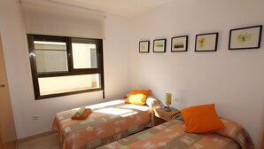 Ein Zimmer mit zwei Betten, einem Fenster und vier gerahmten Bildern an der Wand.