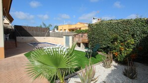 Ein Garten mit Swimmingpool, einer Palme und einer Hecke.