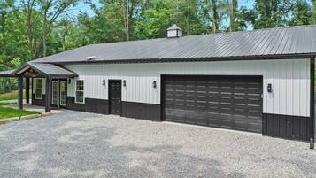 A building with a garage door, a covered porch, and a gravel driveway.