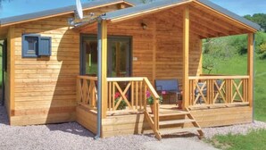 A wooden cabin with a porch, a satellite dish, and a gravel driveway. - Cozy Chalet with Spa and Pets Allowed near Plombières-les-Bains (Fougerolles-Saint-Valbert)