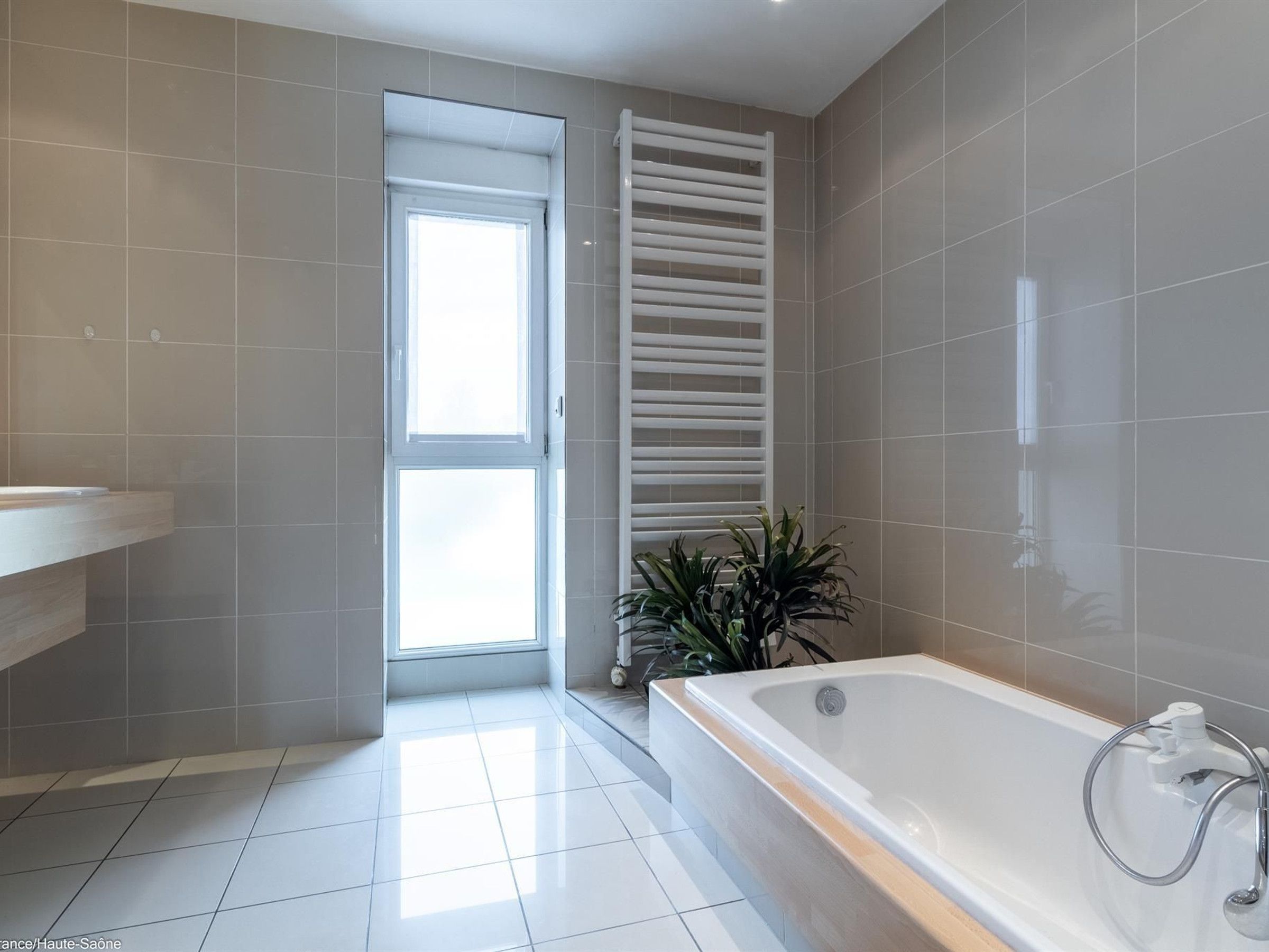 Un baño moderno con bañera, ventana y un perchero para toallas.